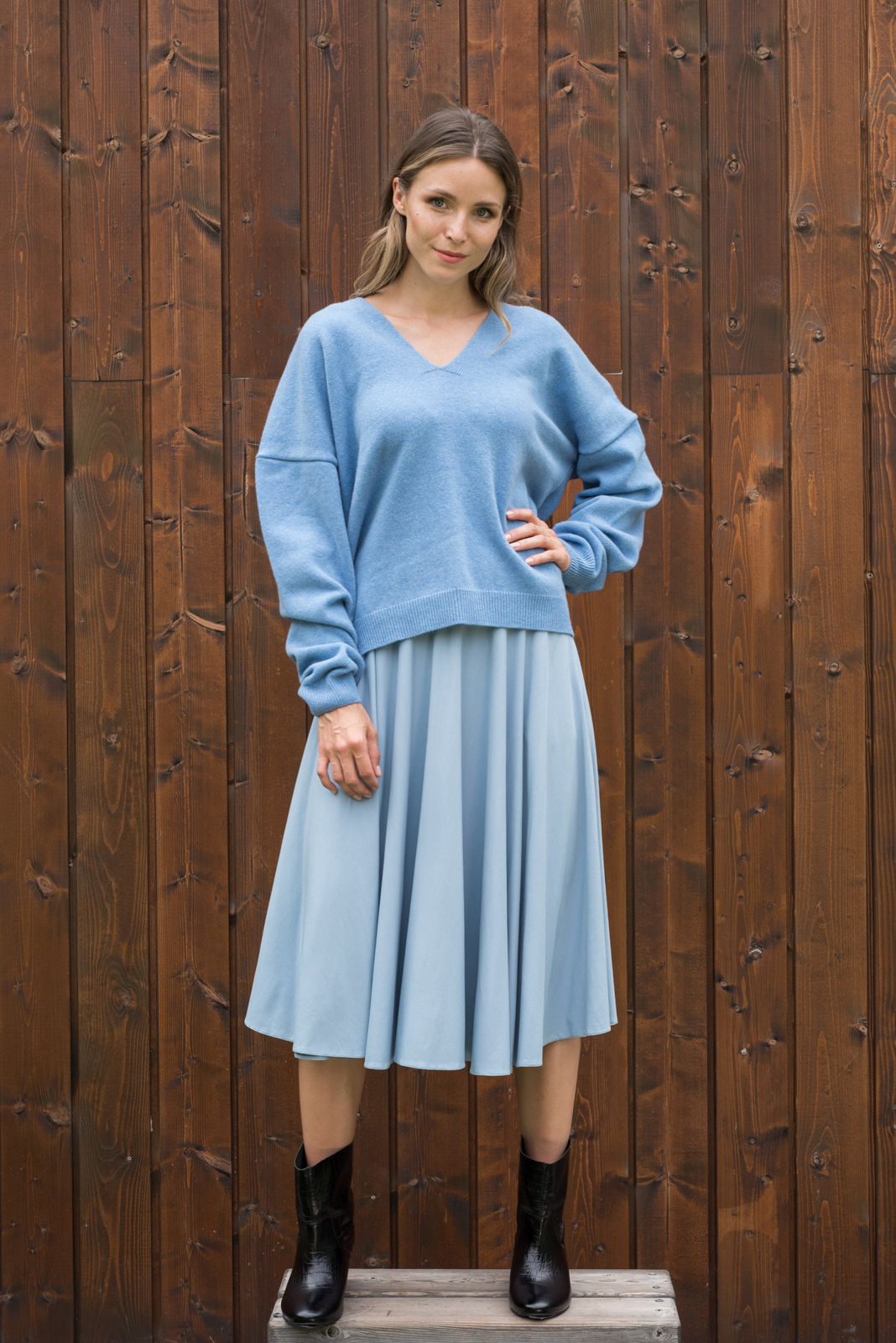 Błękitny sweter oversize w zestawieniu z niebieską plisowaną spódnicą